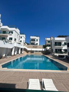 a swimming pool with two lounge chairs and some buildings at PLEASENT SUNSET in CESME-SITE SOLEY 17 in Çeşme