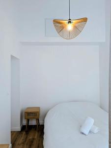 a bedroom with a white bed and a pendant light at Maisonnette proche centre ville et plage in Saint-Brevin-les-Pins