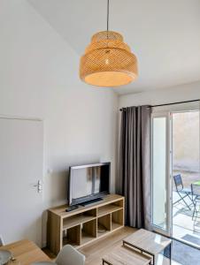 a living room with a television and a table at Maisonnette proche centre ville et plage in Saint-Brevin-les-Pins
