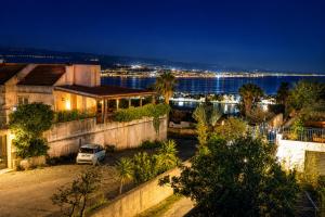 a house with a car parked in front of the water at Aloha Village - Bed&Pet in Messina