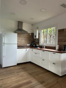 a kitchen with white cabinets and a white refrigerator at Villa Remedios -rooms in private house- in Picassent