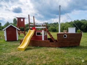 a wooden playground with a slide and a house at Ventspils Podnieki in Ventspils