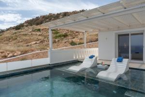 a house with a swimming pool with two chairs at Aqua Blue Villa in Amoopi