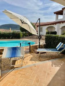 a pool with two chairs and an umbrella in front of a house at Mediterranean Sea Shell Pool House in Budoni