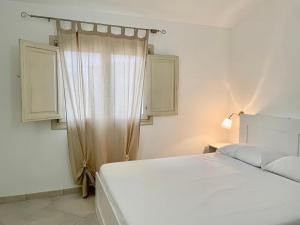 a bedroom with a white bed and a window at Mediterranean Sea Shell Pool House in Budoni