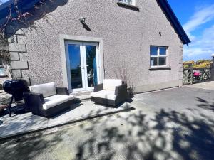 a patio with two chairs and a window at The Nook at Ballyward Croft in Ardkeen