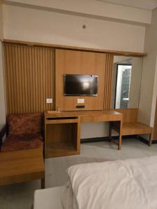 a room with a tv and a desk with a bed at Atithi Palace in Bhāgalpur
