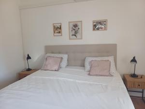 a white bed with two pink pillows on it at Studio apartman Marija in Bol