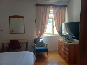 a bedroom with a bed and a tv and a chair at Studio apartman Marija in Bol