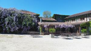 a building with a bunch of purple wisterias at Ferme de L'Aoueille in Pouylebon