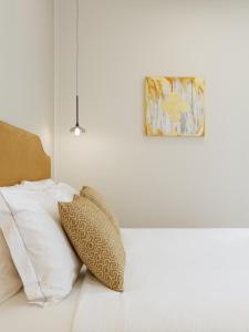 a white bedroom with pillows and a painting on the wall at Neris Boutique Rooms in Muggia
