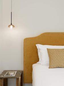 a bed with a wooden headboard and a side table at Neris Boutique Rooms in Muggia