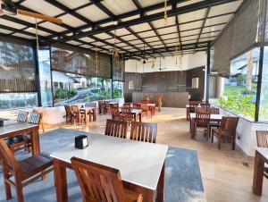 a restaurant with tables and chairs and windows at Coorg Tiger Eye Backwater Resort in Kushālnagar