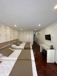 a room with four beds and a flat screen tv at Hostal San Fernando in Santander