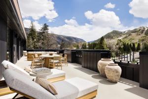 a patio with tables and chairs on a balcony with mountains at White Elephant Aspen in Aspen