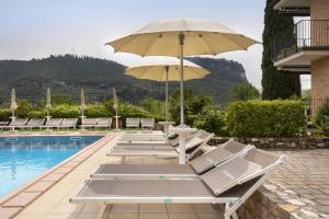a row of lounge chairs and an umbrella next to a pool at Cà Gardesana With Pool in Garda