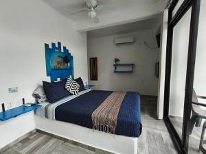 a bedroom with a king sized bed with a blue comforter at teki-sha home&suites in Bacalar