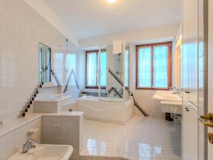 a white bathroom with two sinks and a tub and a bath tub at Villa Manuela by Interhome in Brenzone sul Garda