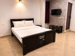 a large bed in a bedroom with a television at Courtyard Residency Thekkady in Thekkady