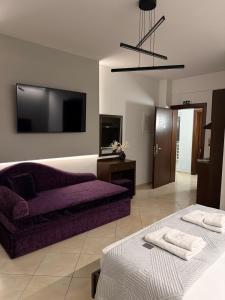 a living room with a purple couch and a tv at MG Luxury Living in Nea Vrasna