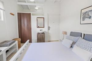 a white bedroom with a bed and a sink at Mandavilla Apartment Curacao in Willemstad