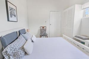 a white bedroom with a bed and a chair at Mandavilla Apartment Curacao in Willemstad