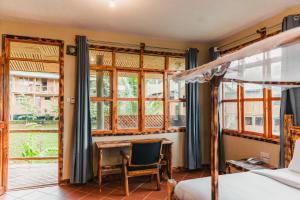 ein Schlafzimmer mit Bett, Schreibtisch und Fenstern in der Unterkunft Forest Sunset Hotel in Morogoro