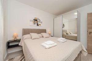 a white bedroom with a bed with towels on it at Nelly Apartments in Privlaka +50 photos