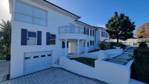 a white house with a balcony and a driveway at Strode House in Knysna