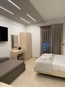 a bedroom with a bed and a couch and a television at MG Luxury Living in Nea Vrasna
