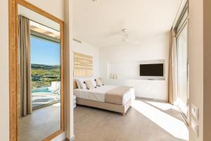 a bedroom with a bed and a large window at Ramnus Karpathos Suites in Karpathos