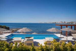 a swimming pool with chairs and umbrellas and the ocean at Villa Giada Luxury Boutique Hotel in Civitavecchia