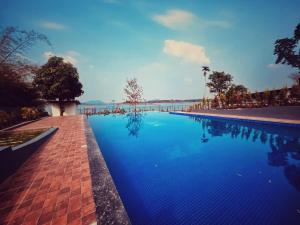 a swimming pool with blue water in a resort at Coorg Tiger Eye Backwater Resort in Kushālnagar