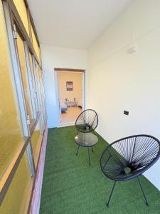two chairs in an empty room with green carpet at Sydney Apartment in Frosinone +15 photos