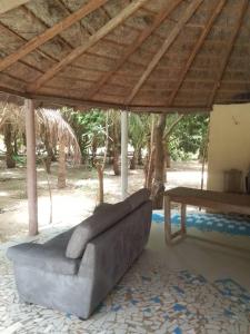 a couch sitting under a pavilion with a table at Ecolodge EcoFarm Fimela in Fimela