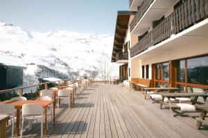 a balcony with tables and chairs and snow covered mountains at Alpeen Hotel in Les Menuires