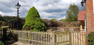a white picket fence with a large tree behind a wooden picket fenceastery at Pinecroft B&B in Lymington