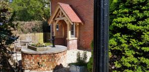 a small brick building with a window and a brick wall at Pinecroft B&B in Lymington