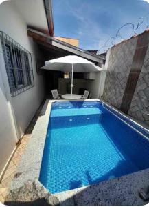 a large blue swimming pool next to a house at Casa de piscina em Delfinopolis área central 2 suítes in Delfinópolis
