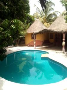 a swimming pool in front of a house with a resort at Ecolodge EcoFarm Fimela in Fimela