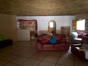 a living room with a red couch and a table at Ecolodge EcoFarm Fimela in Fimela