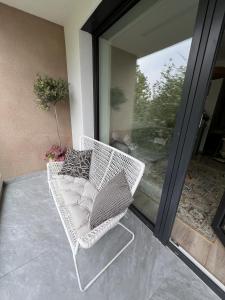 a white wicker chair sitting on a porch at Olive II Apartman in Alsóörs