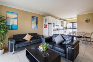 a living room with black leather furniture and a kitchen at Canvas Cúirt na Coiribe Galway in Galway