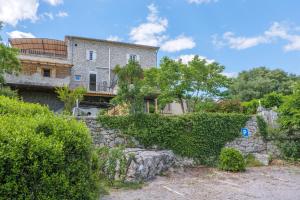 an old house with a stone wall and bushes at Le Mas Boyer in Chauzon
