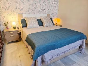 ein Schlafzimmer mit einem Bett mit blauer Bettdecke in der Unterkunft Poly's House in Tomares