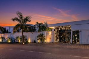 a white building with palm trees in front of it at La Maison Palmier Abidjan, a Member of Design Hotels in Abidjan