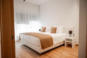 a white bedroom with a white bed and a window at Fruške Residences - Fruške Terme in Vrdnik