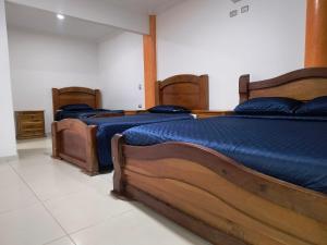 three beds with blue sheets in a room at Hotel Cima Real in Arauca