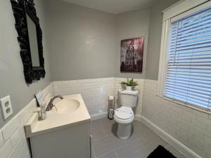 a white bathroom with a toilet and a sink at Downtown Lake Eola Historic House 1 OR 2 BED in Orlando