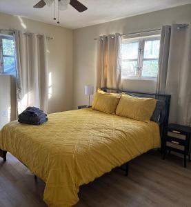 a bedroom with a bed with a yellow comforter and two windows at Vintage 2 Bedroom Condo Lake Eola View in Orlando +26 photos
